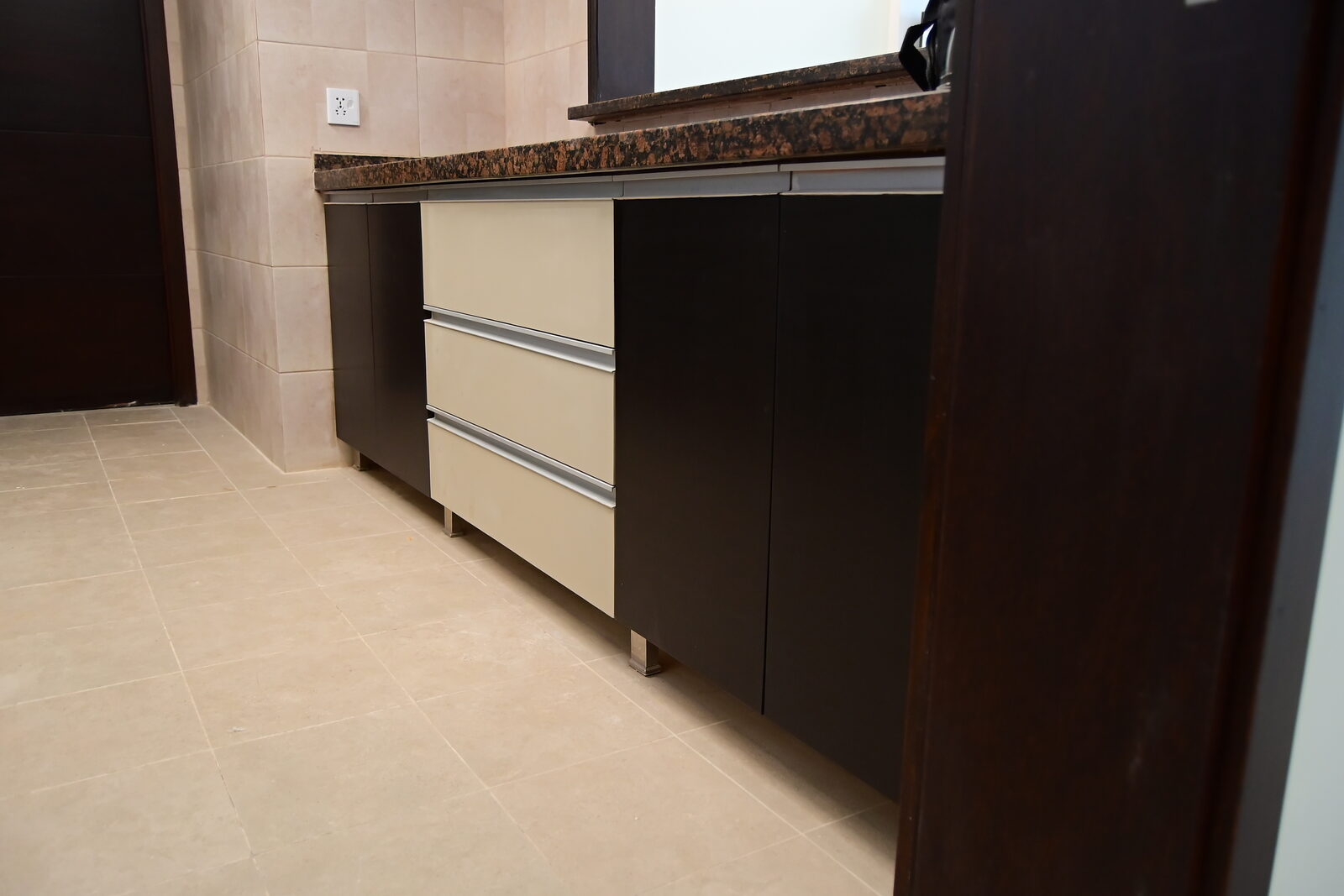Kitchen base units with cream drawer fronts, aluminium handles and stone worktop