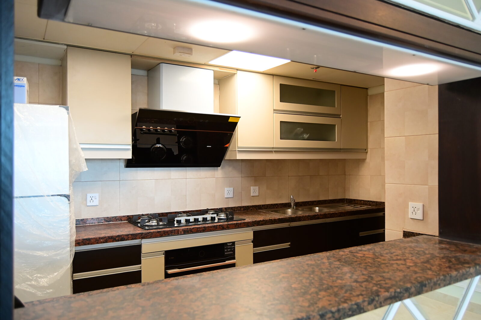 Fitted kitchen with cream wall units, dark base units and stone worktop