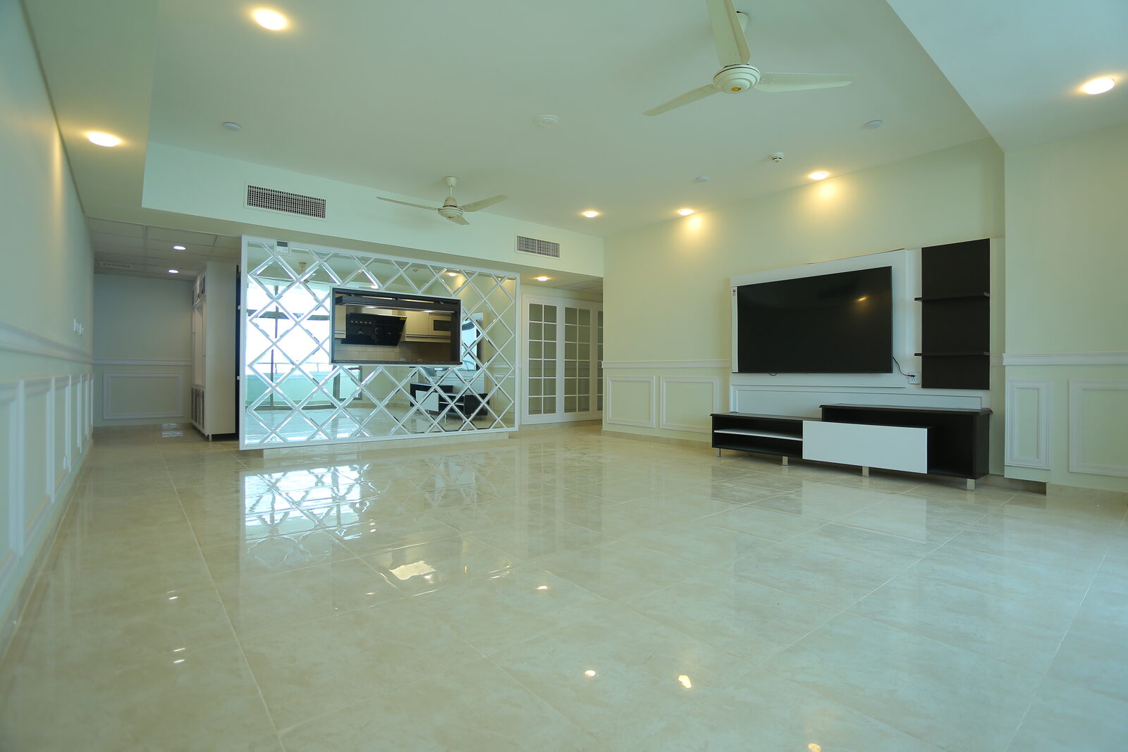 Completed living room with mirrored partition screen, panelled walls and built-in television unit